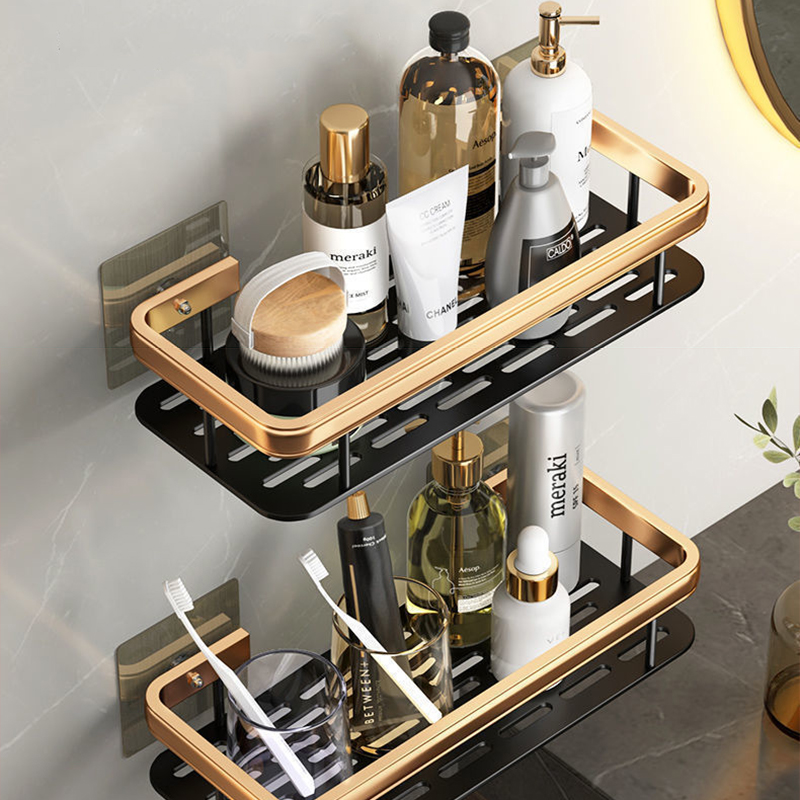 Deux étagères murales noir et or rectangulaire l'une au dessus de l'autre portant de nombreux produits de soin, du savon en bouteille et des brosses a dents