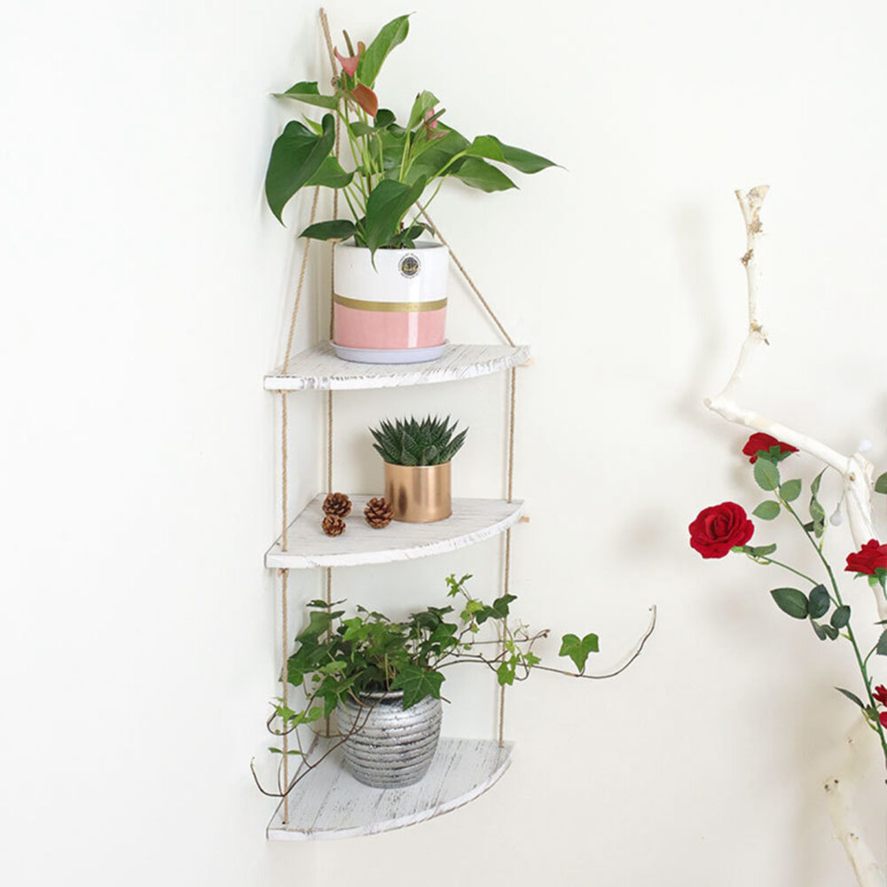 étagère murale d'angle suspendue en bois et corde sur trois étages avec des pots de fleurs dessus.