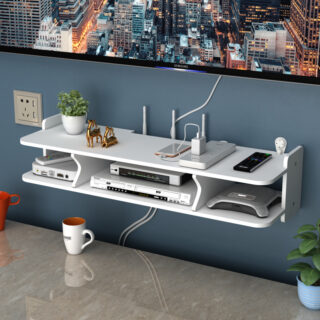 Étagère murale télévision 3 compartiments fixée sur un mur bleu, en dessous d'une télévision écran plat fixée aussi au mur. Des bibelots sont posés sur l'étagère et des accessoires électroniques dans l'étagère. Une tasse est posée sous l'étagère.