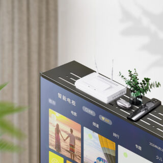 Étagère de rangement télévision fixée sur une télévision écran plat avec posé dessus, une plante, une box et une télécommande