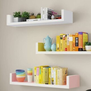 Photo de trois étagères murales avec des livres et objets sur un mur blanc