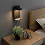 Étagère murale LED design avec port USB installée sur un mur à côté d'un lit et au-dessus d'une table de nuit avec des cadres et un pot de fleur