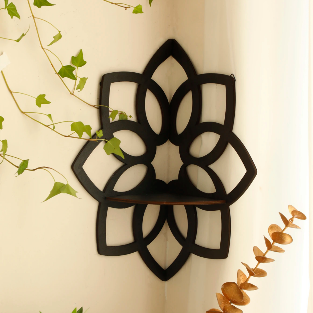 Étagère murale d'angle en forme de fleur noire installée sur un mur beige avec des plantes à gauche et en dessous