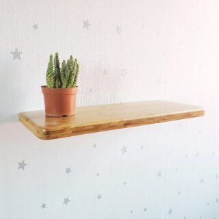 Étagère murale salon en bambou vernis fixée sur une tapisserie avec petit cactus