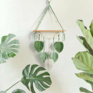 Étagère murale corde avec des décorations style nature sur un mur blanc avec des plantes.