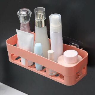 Étagère murale douche avec une attache ventouse ici sur un mur noir. Elle est de couleur rose orangé avec des flacons de cosmétiques dessus.