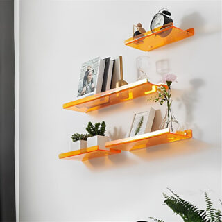 Trois étagères murales en acrylique orange avec trois longueurs différentes.Elles se trouvent les unes sous les autres de la plus petite à la plus longue. Elles ont chacune des objets de décoration.