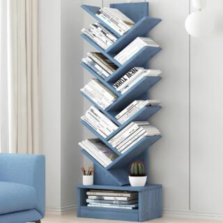 Étagère murale en bois bleu, posé au sol, contre un mur blanc. Elle a une forme d'arbre avec 10 niveaux de rangement ressemblant à des branches.Tous les espaces sont occupés par des livres. La partie du bas contient un espace de rangement supplémentavec des magazines. L'angle d'un canapé bleu se trouve à gauche.