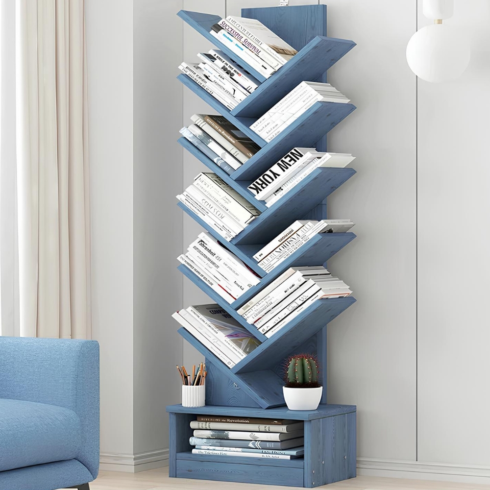 Étagère murale en bois bleu, posé au sol, contre un mur blanc. Elle a une forme d'arbre avec 10 niveaux de rangement ressemblant à des branches.Tous les espaces sont occupés par des livres. La partie du bas contient un espace de rangement supplémentavec des magazines. L'angle d'un canapé bleu se trouve à gauche.