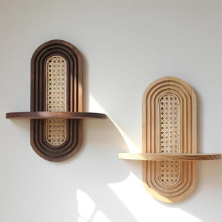 2 étagères murales de forme ovale en bois et cannage au centre avec une tablette en bois. L'étagère de gauche est en bois foncé, celle de droite en bois clair. Sur mur blanc.