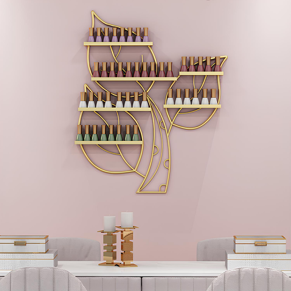 Étagère murale en forme de 3 feuilles dorées sur lesquelles se trouvent des supports avec des vernis de couleur. Fixée sur un mur rose, au-dessus d'une longue table blanche avec des sièges gris.