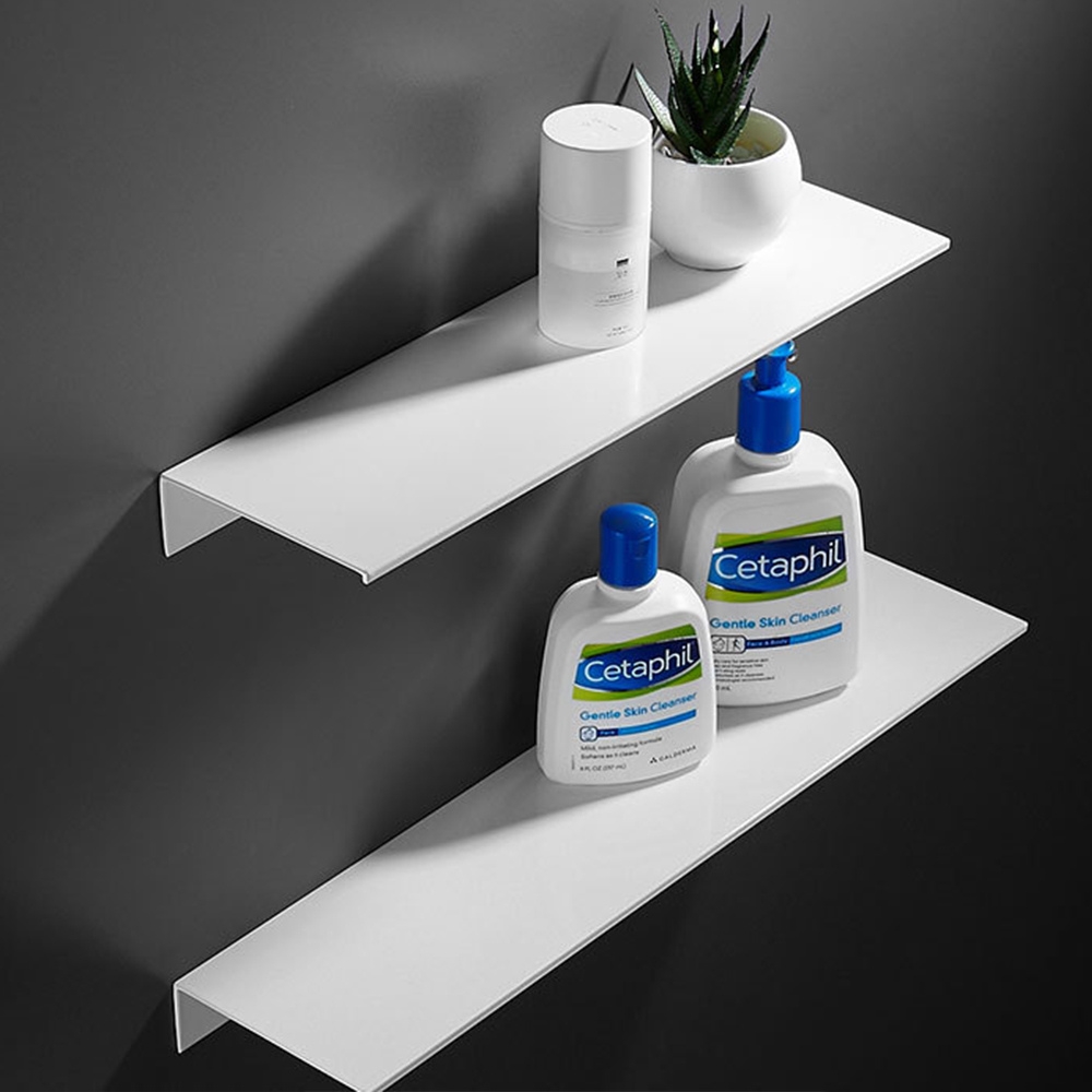 Deux étagères en aluminium blanc, l'une au-dessus de l'autre. Elles sont fixées sur un mur gris foncé. Sur celle du haut, un flacon et une petite plante artificielle, sur celle du bas, deux flacons de cosmétiques.